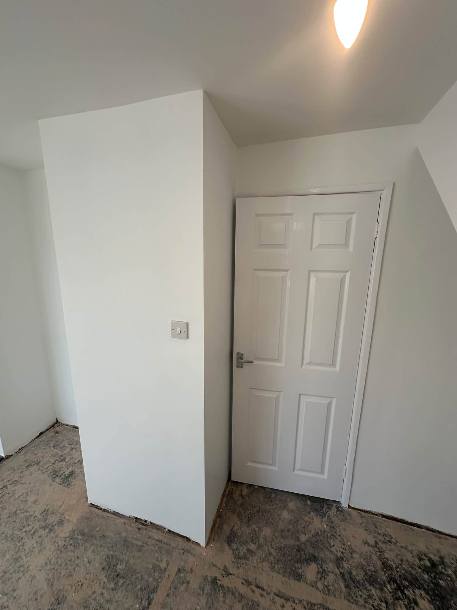White walls with crisp corners around a panelled door beneath the ceiling