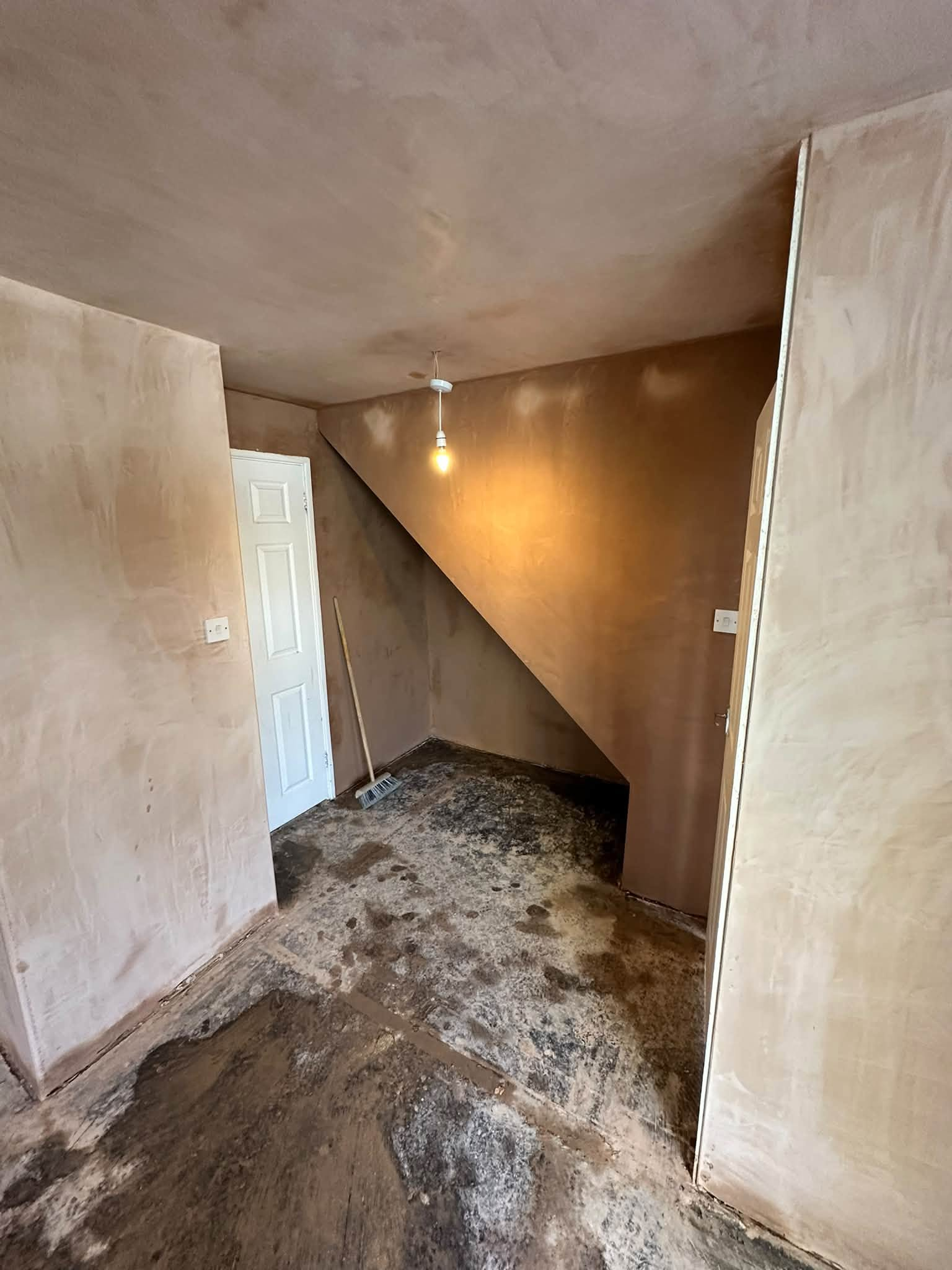 Freshly plastered walls and ceiling around a sloping wall and white doors