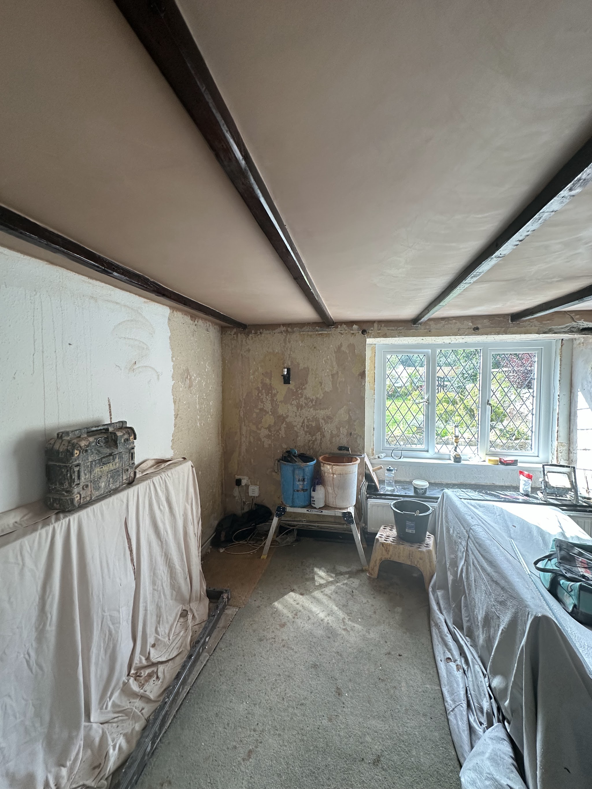 New plaster between exposed ceiling beams in a room being renovated